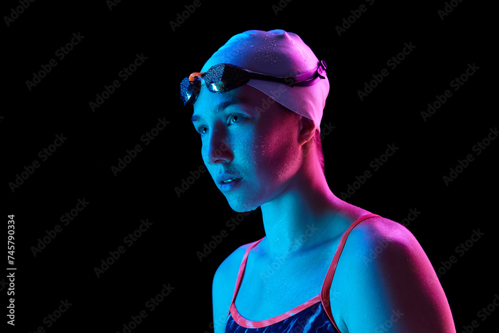 Portrait of skilled, young woman swimmer with water droplets on skin, show intricate in vibrant neon light against black studio background. Concept of professional sport, motion, strength, power. Ad Portrait of skilled, young woman swimmer with water droplets on skin, show intricate in vibrant neon light against black studio background. Concept of professional sport, motion, strength, power. Ad