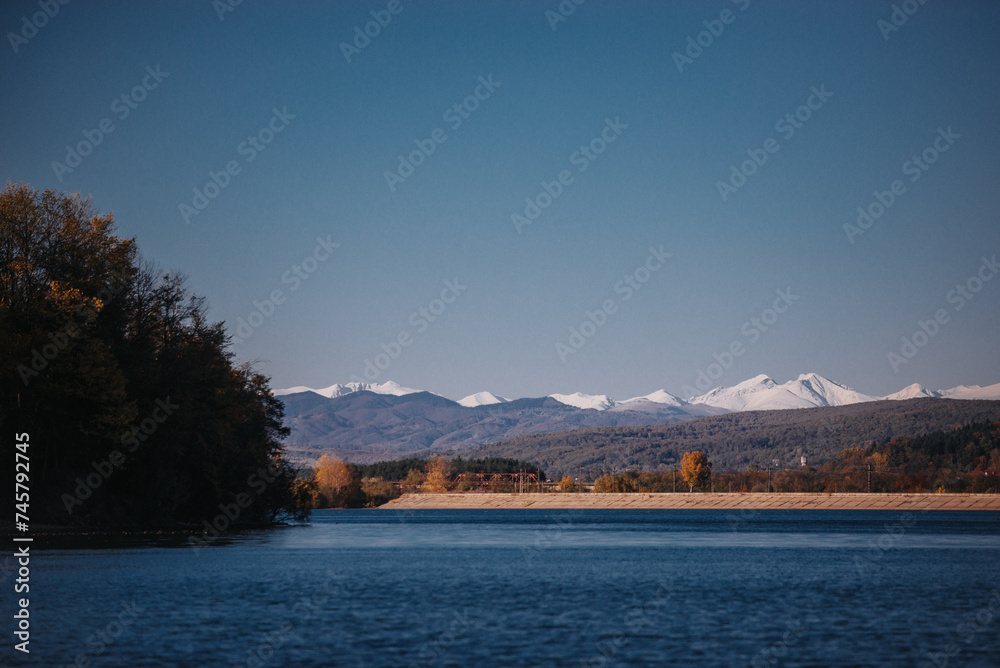 Autumn landscape with a blue lake and mountains in the background. Colorful forest at the edge of the water at the foot of the Carpathians
Autumn landscape with a blue lake and mountains in the background. Colorful forest at the edge of the water at the foot of the Carpathians