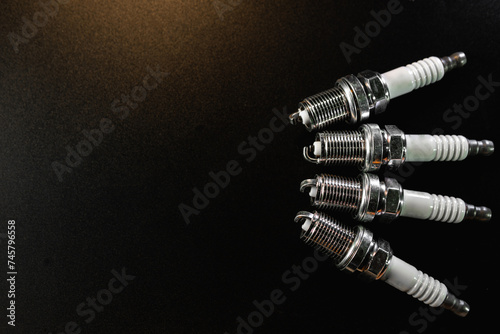 New Spark plugs on black background . car and motorcycle part. The concept of car service, repair. Top down view.