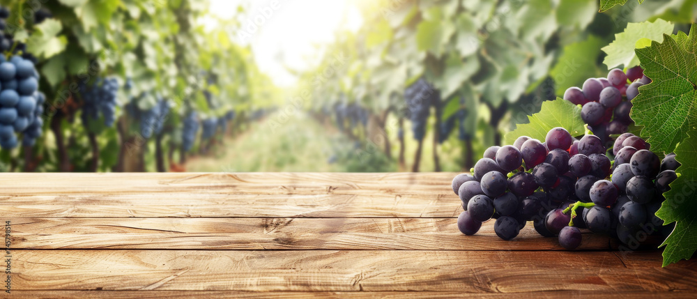 Ripe Grapes on Vineyard Wooden Table, A bountiful bunch of ripe red grapes on an old wooden table with a sunlit vineyard stretching into the distance. - obrazy, fototapety, plakaty 