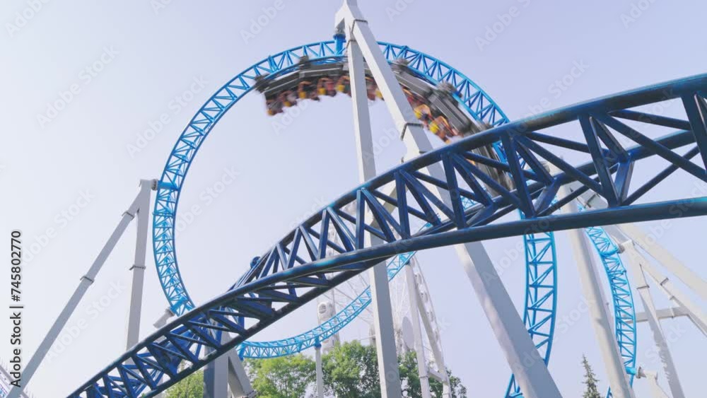 Roller coaster Ride against blue sky. Roller coaster in the amusement park. Cheerful entertainments in park of attractions Roller coaster Ride against blue sky. Roller coaster in the amusement park. Cheerful entertainments in park of attractions