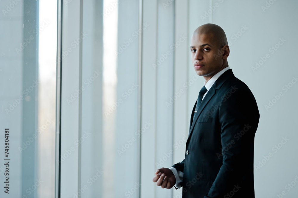 African american businessman in formal wear looking at camera near window in office African american businessman in formal wear looking at camera near window in office