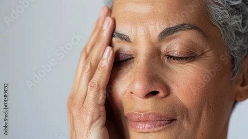 A woman with closed eyes resting her head on her hand appearing contemplative or tired.