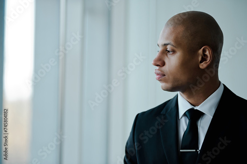 African american manager in classic attire looking at window in office