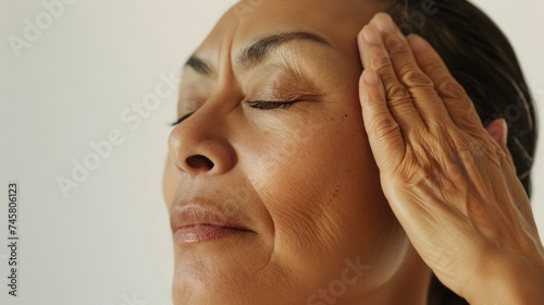 Woman with closed eyes hand on forehead in a state of relaxation or contemplation.