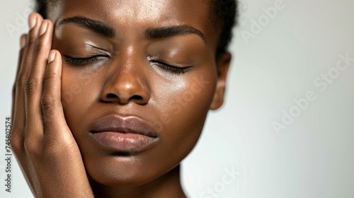 A close-up portrait of a person with their eyes closed resting their head on their hand against a white background conveying a sense of relaxation or contemplation.