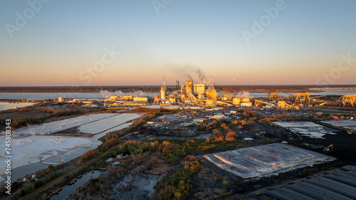 Early morning light bathes a paper mill in Brunswick, Georgia, with storage and industrial activity. photo