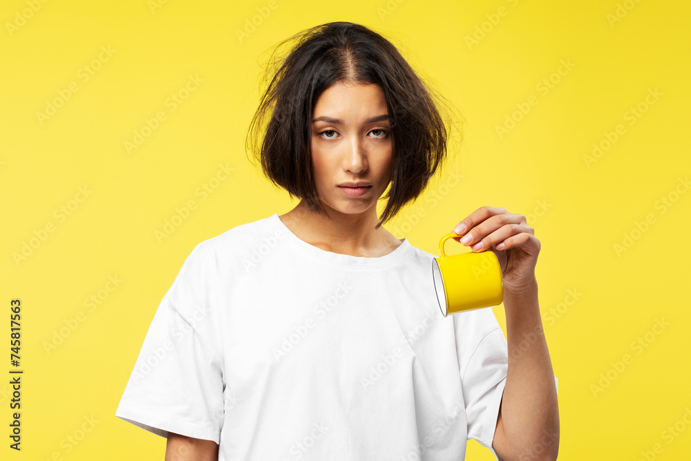 Portrait of tired young pensive Asian woman wearing white t shirt holding cup, wanting to sleep Portrait of tired young pensive Asian woman wearing white t shirt holding cup, wanting to sleep