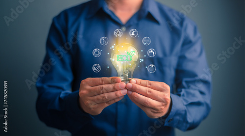 Business man holding light blub with composition clean energy and ecology icons. Save energy and environment concept. Environmental technology concept. Sustainable development goals.