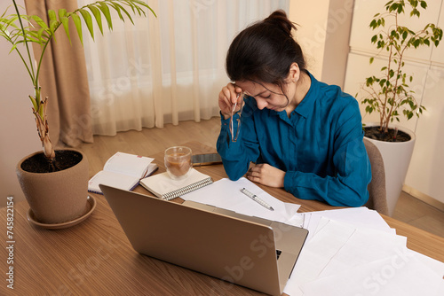 Fotografie Stressed tired woman working at laptop at home
