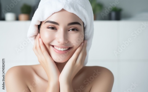 Cheerful woman with towel wrapped head - A radiant woman wrapped in a white towel on her head, posing with hands on cheeks and a joyful expression photo