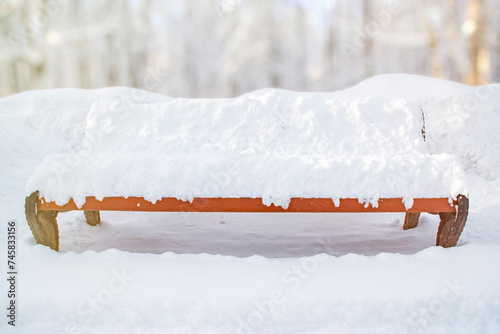 Empty bench in a winter park covered with snow.