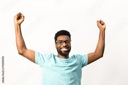 African American man with glasses raises his fists in a triumphant cheer, expressing success and positivity, isolated on a white background, perfect for diverse concepts.
