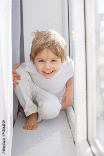 Cute happy toddler boy, child in white cloths, smiling at camera