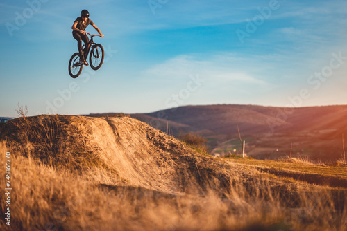 Young man on a mountain bike performing a dirt jump