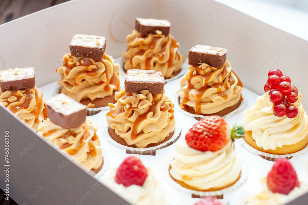 Set of different delicious cupcakes with fresh berries in a paper box on wooden background, horizontal Set of different delicious cupcakes with fresh berries in a paper box on wooden background, horizontal
