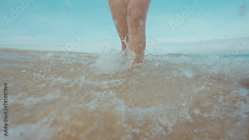 Girl running on the white sand beach, water splashing into the camera slow motion, rescue cabin in the background