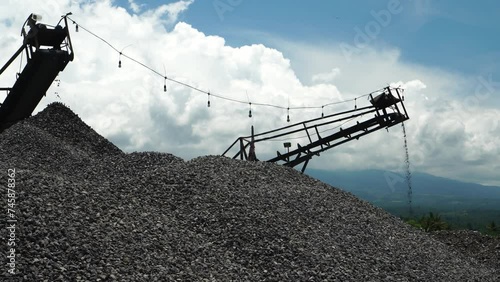 gravel from a natural stone crushing machine in piles with a background of sky and mountains photo