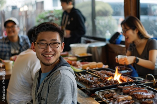 Smiling Young Asian Man with Glasses Enjoying a Barbecue Party with Friends