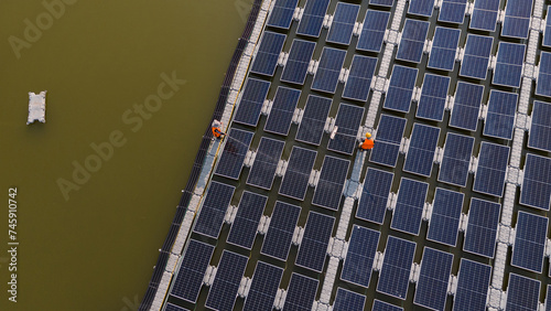 Professional workers cleaning and inspecting solar panels on a floating buoy. Power plant with water, renewable energy sources, Eco technology for industrial electrical energy.