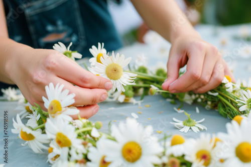 person creating a flower crown with daisies photo
