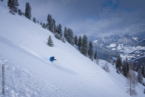 Skiing in deep powder snow in the mountains of Austria during winter, blue sky, in Hochfügen, mountain scenery in background.