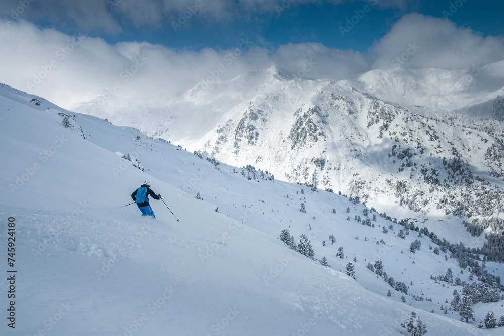 Skiing in deep powder snow in the mountains of Austria during winter, blue sky, in Hochfügen, mountain scenery in background.