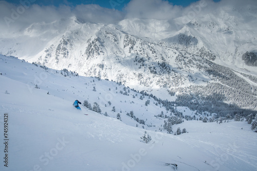 Skiing in deep powder snow in the mountains of Austria during winter, blue sky, in Hochfügen, mountain scenery in background.