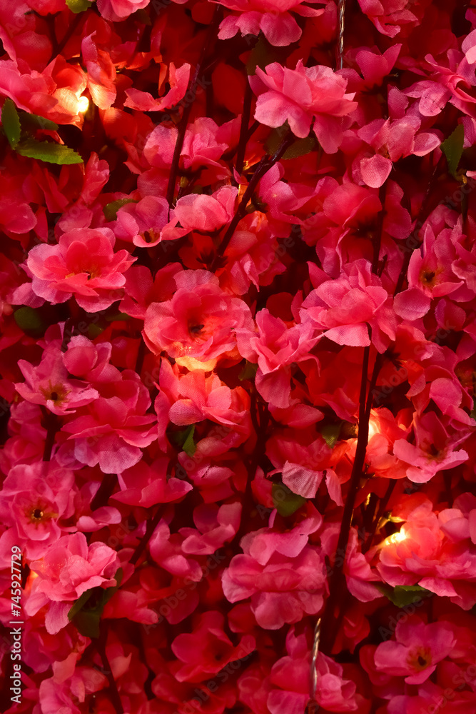 Close-up of the artificial pink flowers with lighting. Flower decoration. Flower background. Close-up of the artificial pink flowers with lighting. Flower decoration. Flower background.