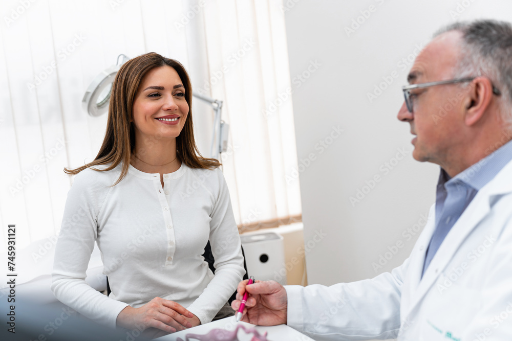 Obraz premium Doctor gynecologist having consultation with patient. The doctor uses the model to explain to the patient the functioning of the female reproductive system, possible problems and their prevention.