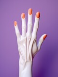 A white mannequin hand with orange nail polish against a purple background