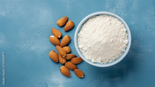 A bowl of almond flour next to whole almonds on a blue background