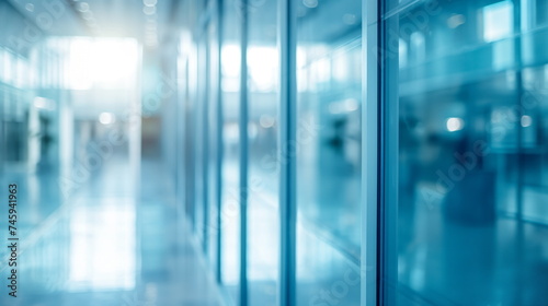Blurred view of a modern office building interior with glass walls, reflecting a cool blue tone and exuding a sleek corporate atmosphere