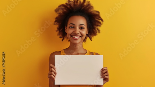 Beautiful young woman smiling, holding a blank sign in front of her. Lovely woman grins with warmth, showcasing blank sign held before her, offering a canvas for your message or branding needs