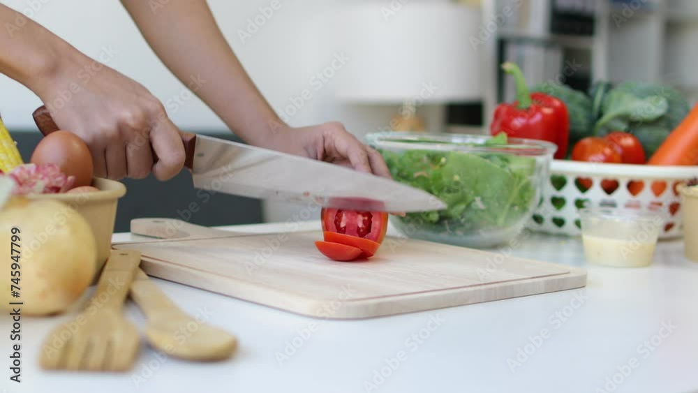 A young woman with a figure is picking vegetables and cutting them, making a salad in the kitchen at home. Happy woman is preparing a fresh healthy salad with many vegetables in the kitchen. A young woman with a figure is picking vegetables and cutting them, making a salad in the kitchen at home. Happy woman is preparing a fresh healthy salad with many vegetables in the kitchen.