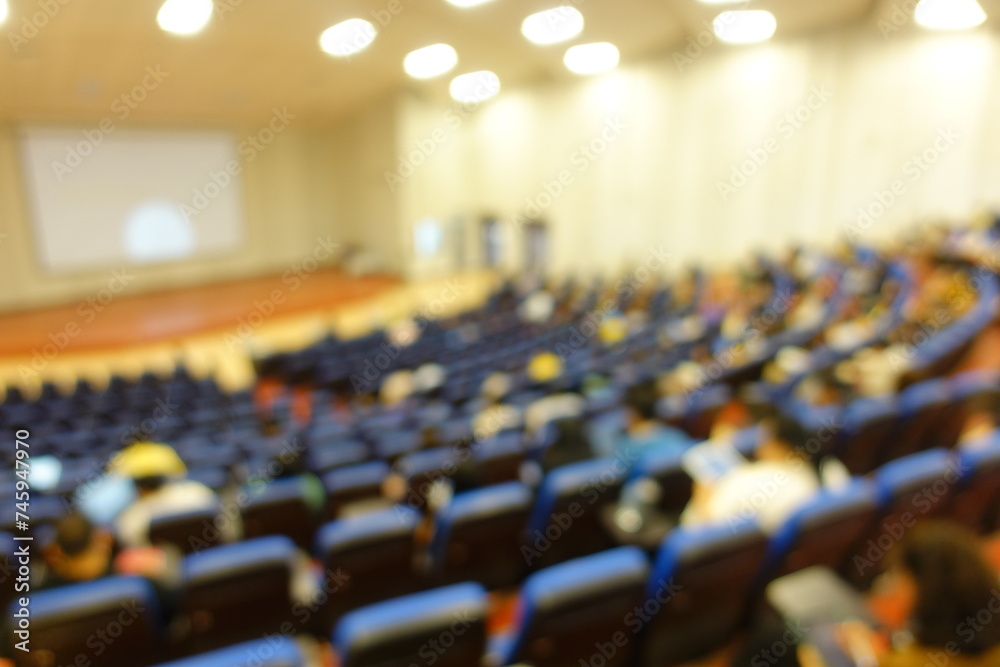 Naklejka premium blurred or defocused people in the seminar convention hall. Business meeting for a press conference or lecturer education concept with a wide view from the room's corner. Modern, blurry auditorium.