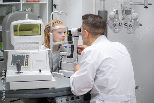 doctor and young patient in eye clinic, girl undergoing an eye test with professional optometrist using advanced diagnostic equipment, pediatric ophthalmology examination