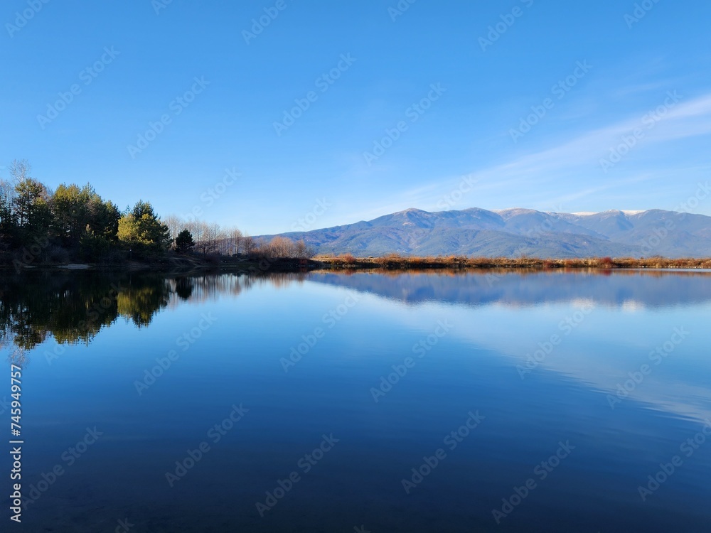 Amazing blue water lake and blue sky reflection with mountains reflecting in background, in Bansko