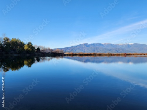 Amazing blue water lake and blue sky reflection with mountains reflecting in background, in Bansko