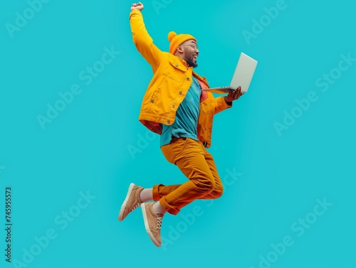 A man jumping with a laptop in his hand on a light blue studio background