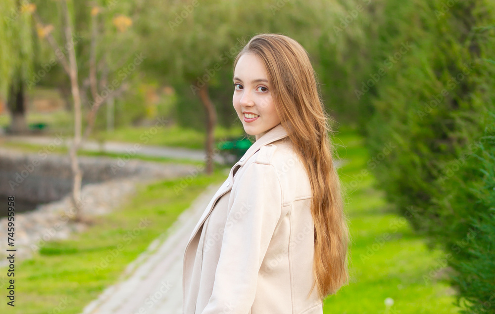 A young smiling girl walking in an autumn park in a good mood. Teenage girl, portrait against a background of nature. Fashion style trend. A young smiling girl walking in an autumn park in a good mood. Teenage girl, portrait against a background of nature. Fashion style trend.