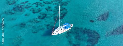 Aerial drone ultra wide photo of sail boat anchored in tropical exotic turquoise calm waters forming a blue lagoon © aerial-drone