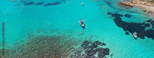 Aerial drone ultra wide photo of sail boat anchored in tropical exotic turquoise calm waters forming a blue lagoon