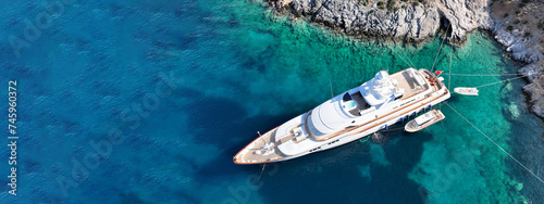 Aerial drone ultra wide top down photo with copy space of luxury yacht anchored in tropical exotic island with crystal clear turquoise sea