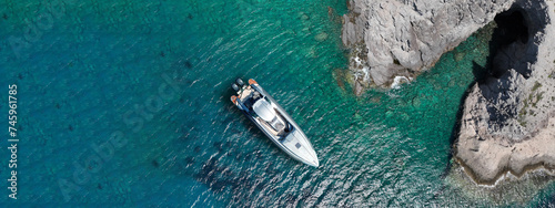 Aerial drone ultra wide photo of inflatable rib power boat anchored in tropical exotic bay with emerald sea and caves