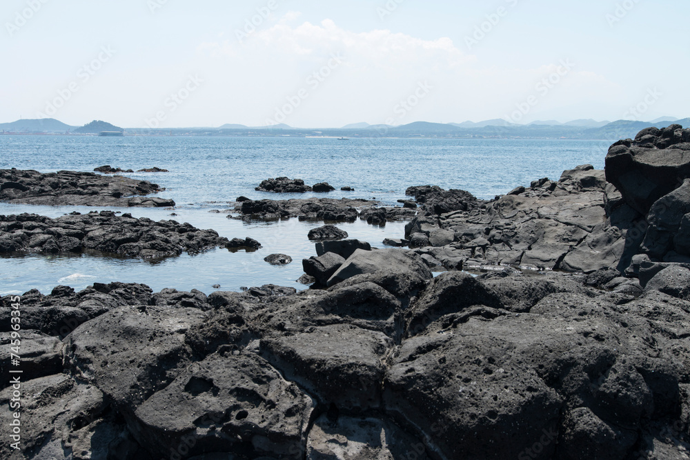 The beach of black rocks at the island seaside