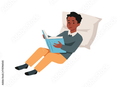 A teenage boy lies on a pillow, deeply immersed in a book.