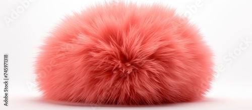 A soft pink fur ball is placed on a plain white surface, showcasing its fluffy texture and vibrant color. The contrast between the pink fur and white background creates a visually striking image.