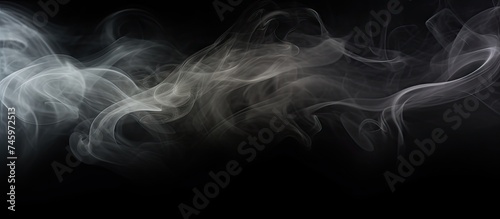 A black and white picture showing abstract smoke creating a textured frame on a dark black background. The swirling patterns of the smoke give a mysterious atmosphere.