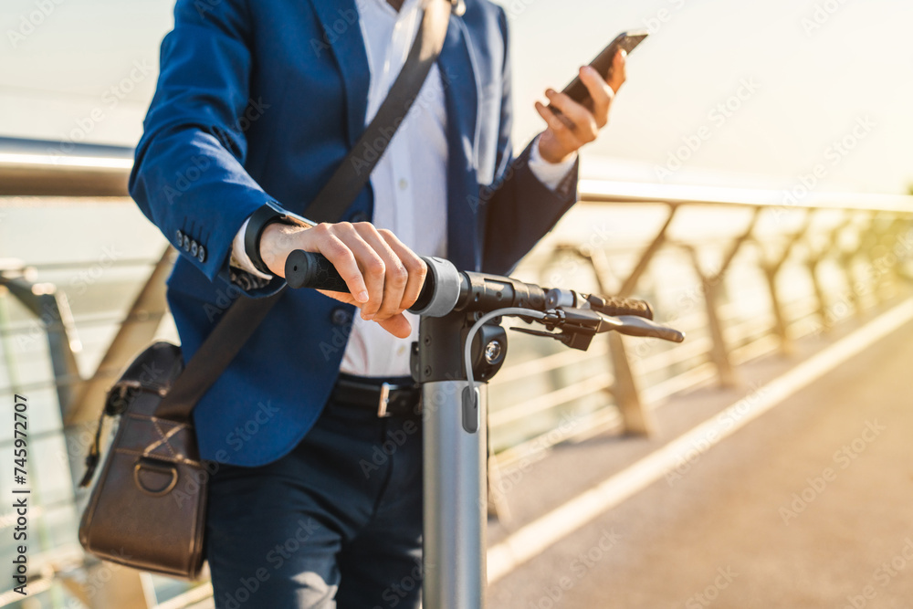 Cropped image of businessman using phone on his electric scooter. Closeup photo of man in business formal attire unlocking e-scooter in mobile application